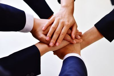 Cropped image of business colleagues stacking hands against white background