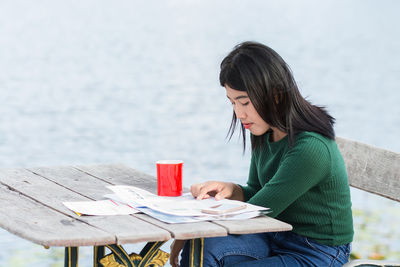 Young woman reading document by coffee on table at sidewalk cafe