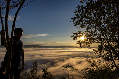 A male traveler exploring foggy top of mountain and looking at sunrise over mae khong river