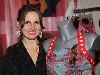 Portrait of smiling woman standing by mannequin