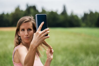 Portrait of woman using mobile phone on field