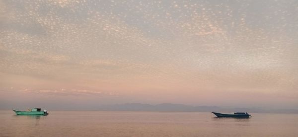 Boat sailing in sea against sky during sunset