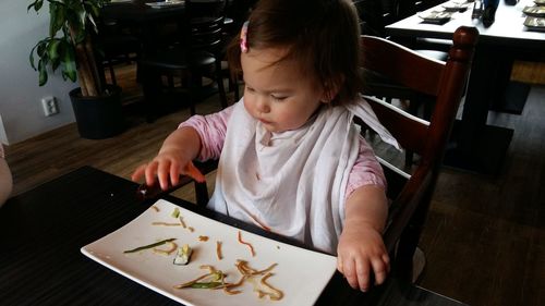 High angle view of girl sitting on table at home