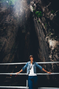 Portrait of young woman standing against rock formation