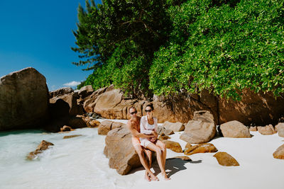 Couple sitting on rock at beach