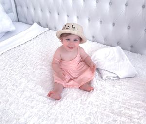 Portrait of cute baby girl on bed at home