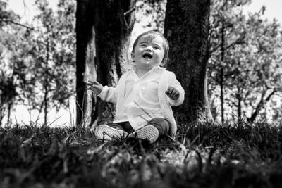 Full length of cute baby boy sitting on grassy field