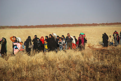 Group of people on field against clear sky