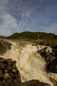 Scenic view of waterfall against sky