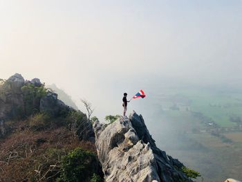 High angle view of man holding thai flag while standing on rock 