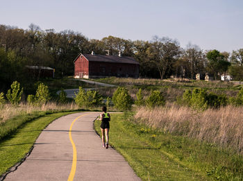 Rear view of woman running on road against sky