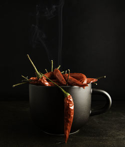 Close-up of red chili peppers on table against black background