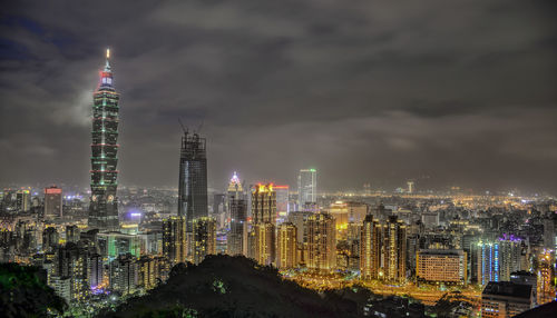 Illuminated modern buildings against sky at night