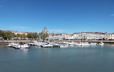 Boats in harbor against clear blue sky