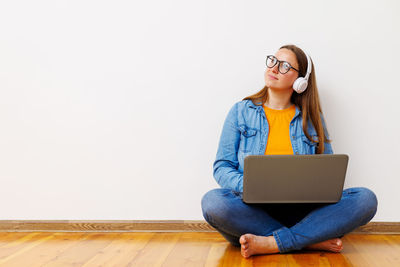 Young woman using laptop while sitting on sofa at home