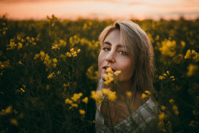 Portrait of young woman with yellow flowers on field