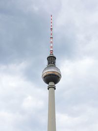 Low angle view of communications tower against cloudy sky