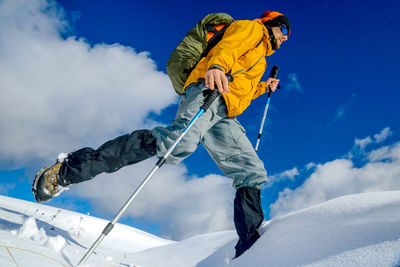 Low angle view of man hiking on snow against sky
