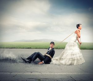 Young couple sitting on landscape against sky