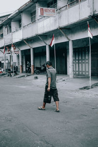 Full length rear view of man walking on building in city