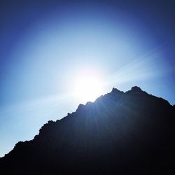 Low angle view of sun shining through clouds