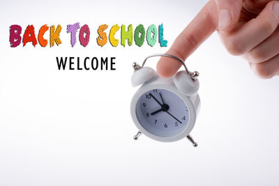 Hand holding clock against white background