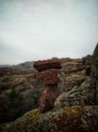 Close-up of rusty metal on rock against sky
