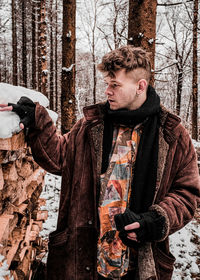 Young man standing by tree during winter