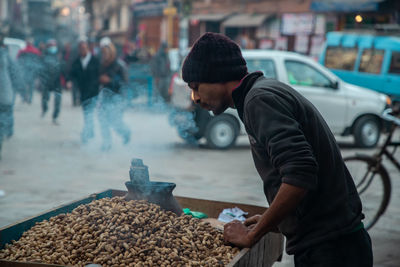 Side view of man standing on street in city