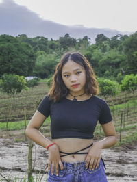 Portrait of young woman standing on field