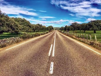 Empty road along landscape and trees against sky