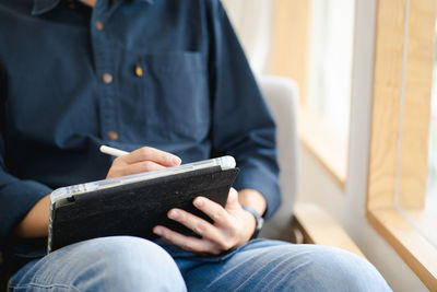 Midsection of woman using digital tablet at home