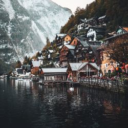 Houses by river and buildings against mountain