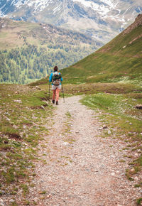 Rear view of woman walking on footpath against mountains