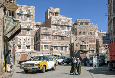 Cars on street by buildings against sky in city