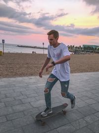 Full length of man on beach against sky during sunset