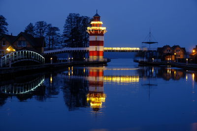 Illuminated bridge over river against sky at night