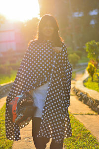 Portrait of woman walking at park during sunset