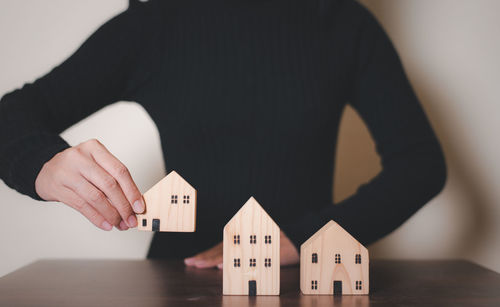 Midsection of man holding model house against white background