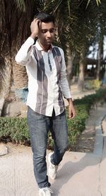 Young man looking away while standing on footpath