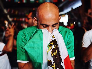 Bald man with eyes closed holding flag
