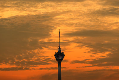 Low angle view of communications tower against cloudy sky