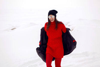 Girl running in a snowy field in a jacket and sunglasses