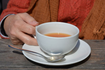 Close-up of woman holding coffee cup on table