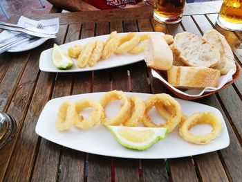 High angle view of onion rings with lime slices in plate and bread on table