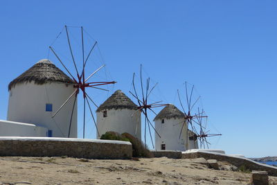 Low angle view of traditional windmills against clear blue sky