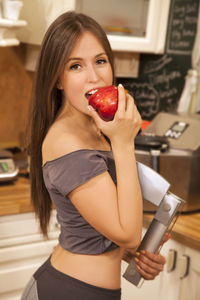 Portrait of young woman holding red while standing outdoors