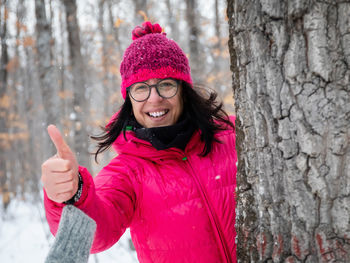 Portrait of smiling young woman standing against pink during winter