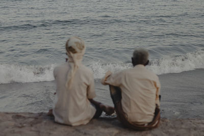 Rear view of couple sitting on beach