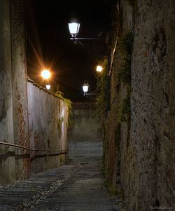 Empty street amidst illuminated buildings at night